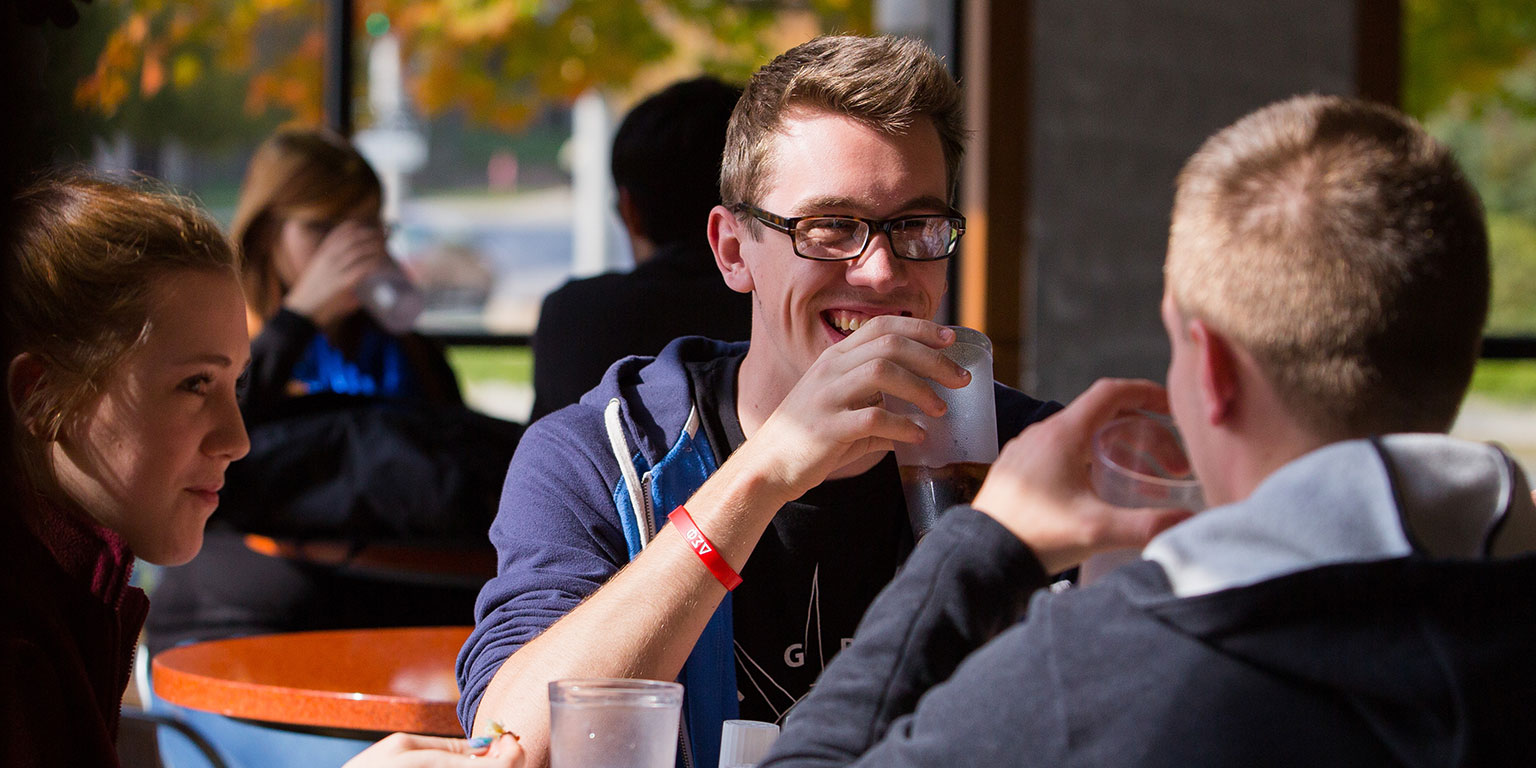 Students at a table eat on campus.