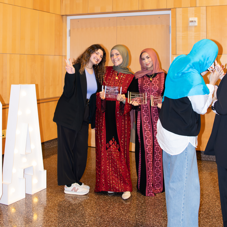 3 Women posing and holding awards.