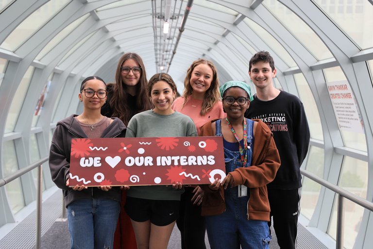 Student Employees for the Marketing and Communications Team holding a sign that says "We Heart our Interns".